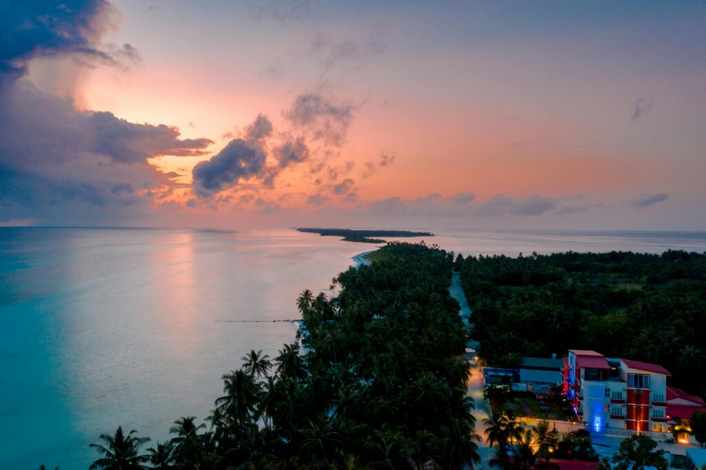 Aerial sunrise view over a Maldives local island with calm ocean and palm trees budget travel