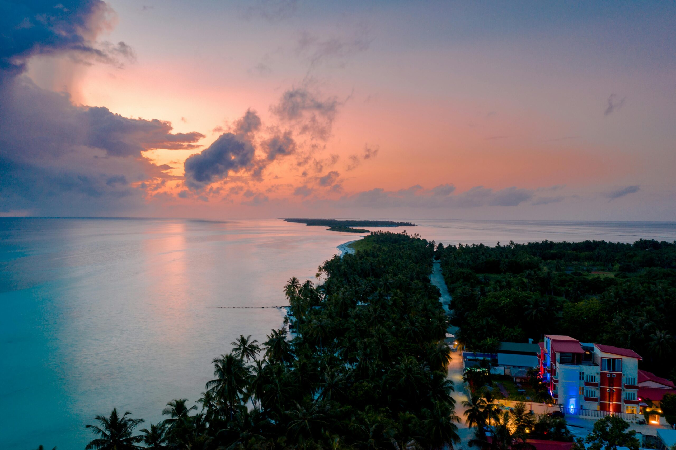 Aerial sunrise view over a Maldives local island with calm ocean and palm trees budget travel