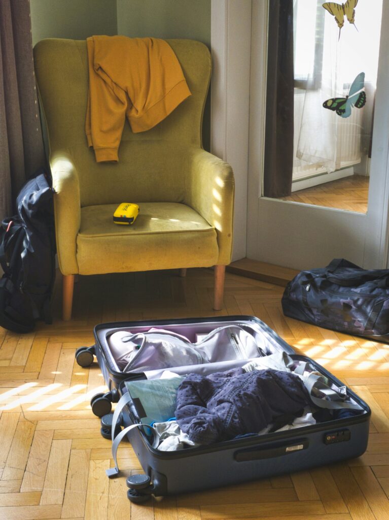 Overpacked suitcase on the floor with a hoodie on a chair showing what not to pack for the Maldives