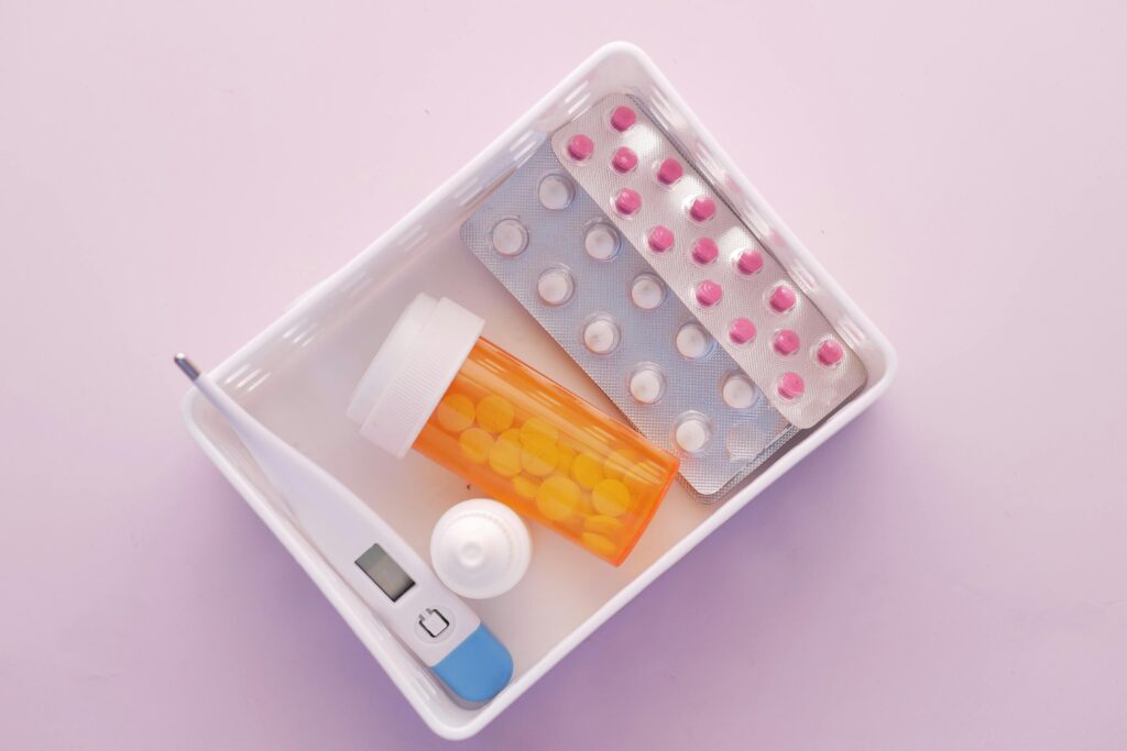 Travel medication kit with pill blister packs, medicine bottle and thermometer in a white box